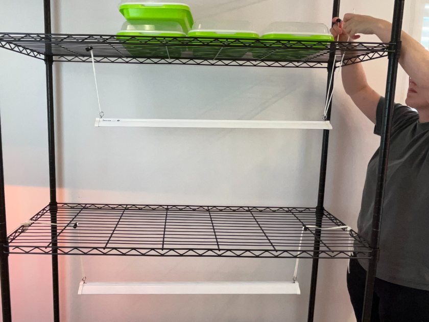 a person hanging their grow light on a wire shelving unit